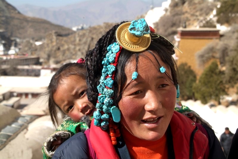 tibet6 005 tibeterin mit kopfschmuck traegt ihr kind auf dem ruecken